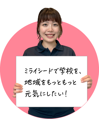 笑顔の女性が「ミライシードで学校を、地域をもっともっと元気にしたい！」と書かれたボードを持っている画像です。