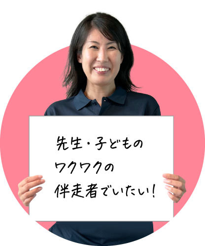 笑顔の女性が「先生・子どものワクワクの伴走者でいたい！」と書かれたボードを持っている画像です。