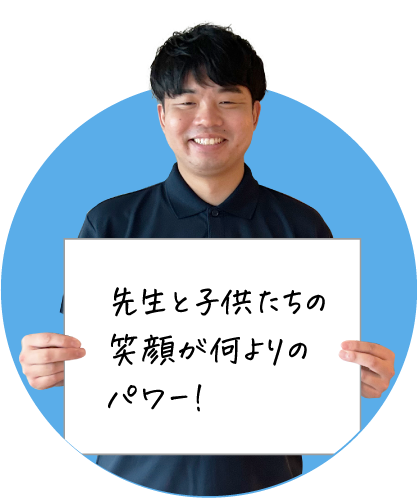 笑顔の男性が「先生と子供たちの笑顔が何よりのパワー！」と書かれたボードを持っている画像です。